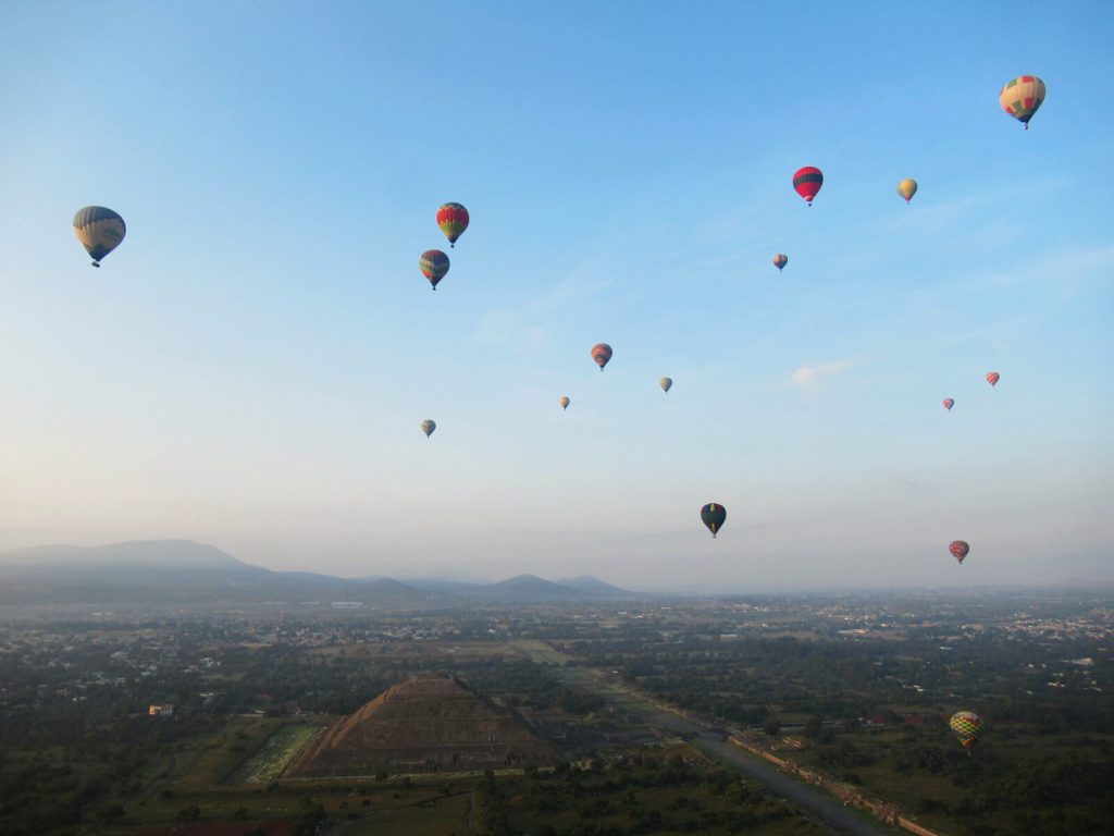 Many hot air balloons over an ancient pyramid in Mexico City