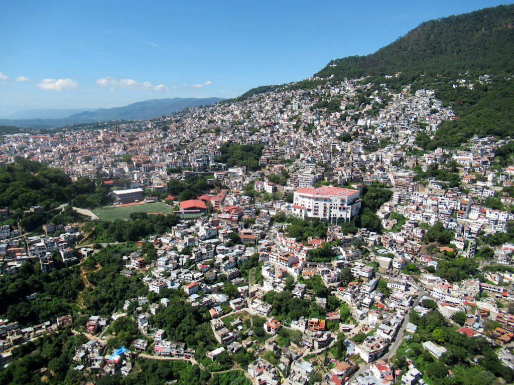 Bird's eye view of the many white buildings of Taxco climbing up the side of the mountain