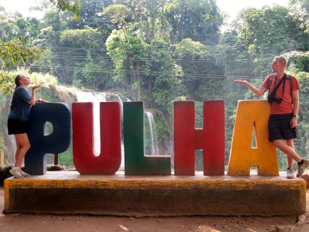 Zoe and Adam stood next to the PULHA sign, they are blowing each other kisses